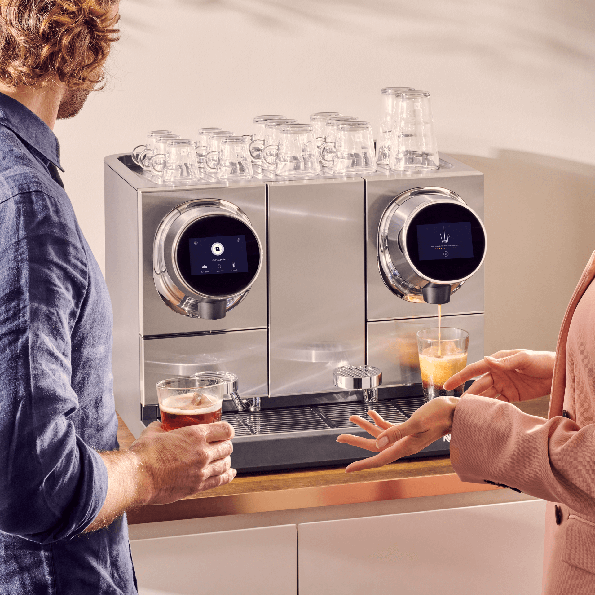 Two colleagues chatting while using Nespresso coffee machine